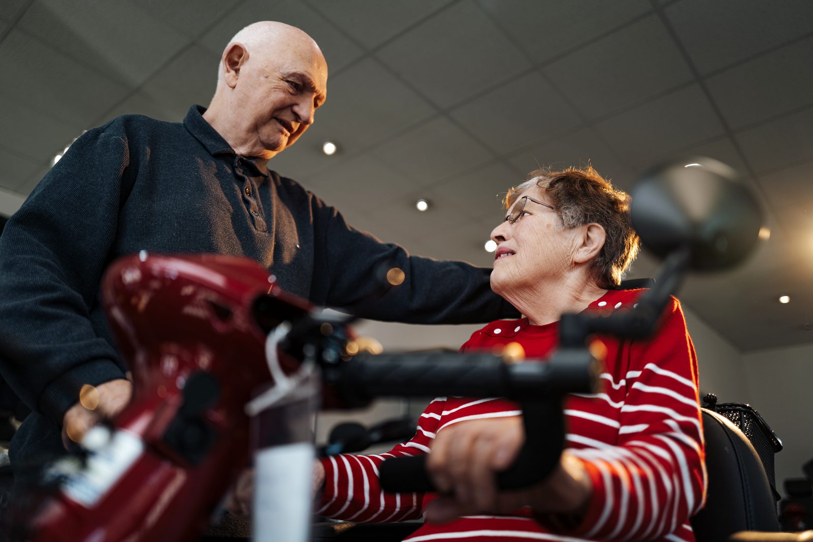 Seniorenpaar bei der Probefahrt mit einem Elektromobil in der Ausstellung