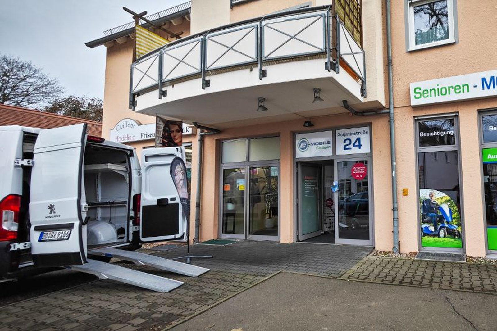 Lieferwagen von E-Mobile Sachsen mit Verladerampe vor dem Ladengeschäft